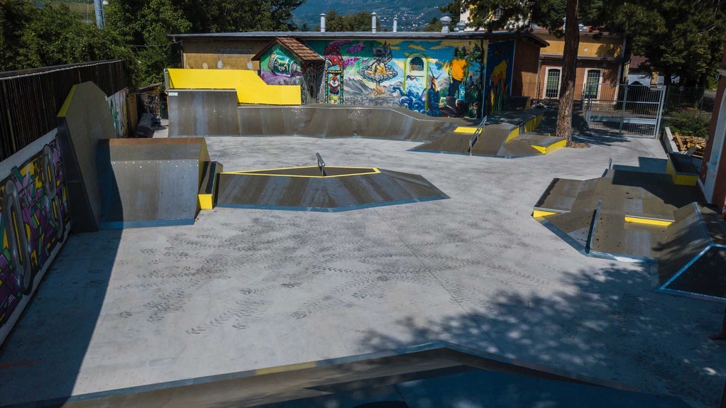 Wide-angle shot showing the diverse concrete and timber ramp setups at Meran skatepark.