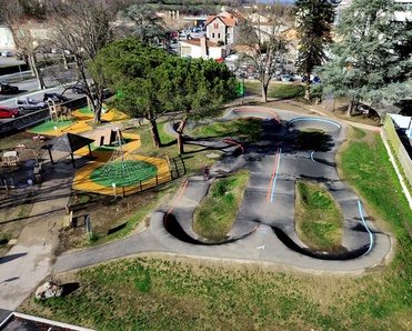 Luftaufnahme des Pumptracks und des angrenzenden Spielplatzes in Saint-Girons mit einem Radfahrer auf der Strecke.