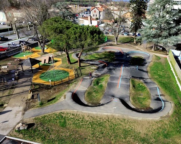 Aerial view of the pumptrack and adjacent playground in Saint-Girons with a cyclist on the track.