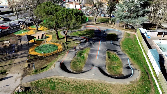Aerial view of the pumptrack and adjacent playground in Saint-Girons with a cyclist on the track.
