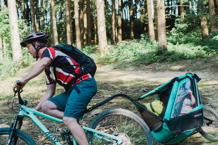Mountainbiker mit Kinderanhänger der Trail herunterfährt