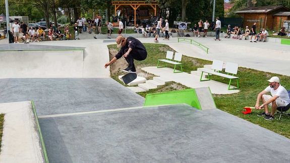 Skater macht einen Kickflip über eine Rampe im Skatepark Stockerau bei einem Event mit Zuschauern.