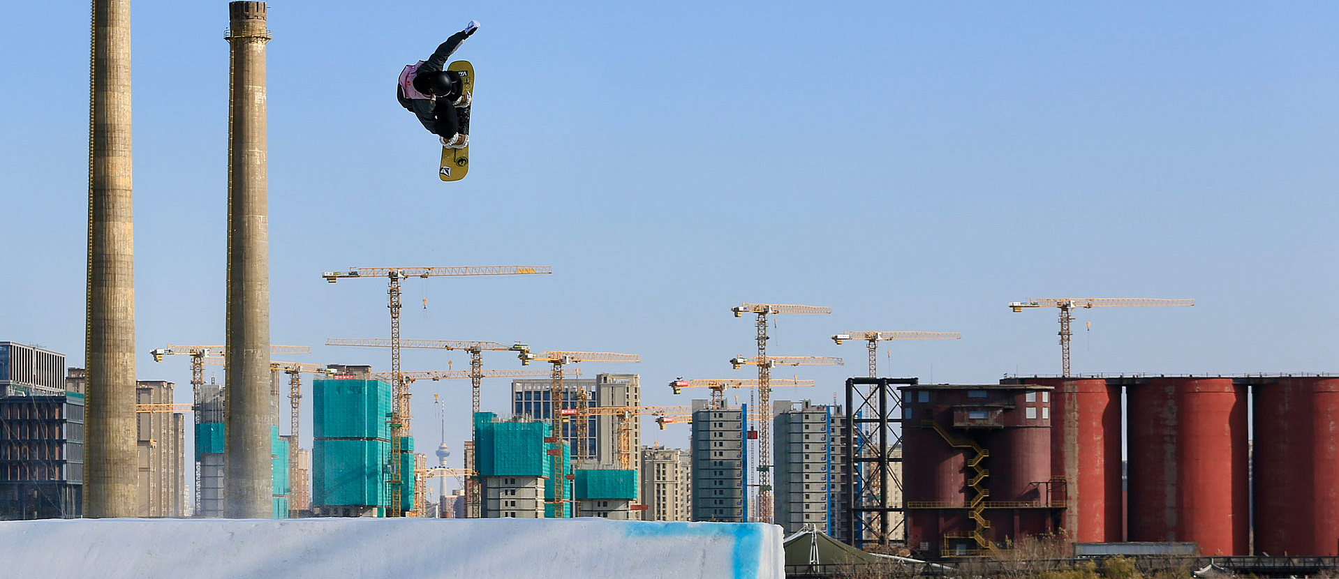 Snowboarderin vor Baukränen im Big Air Sprung