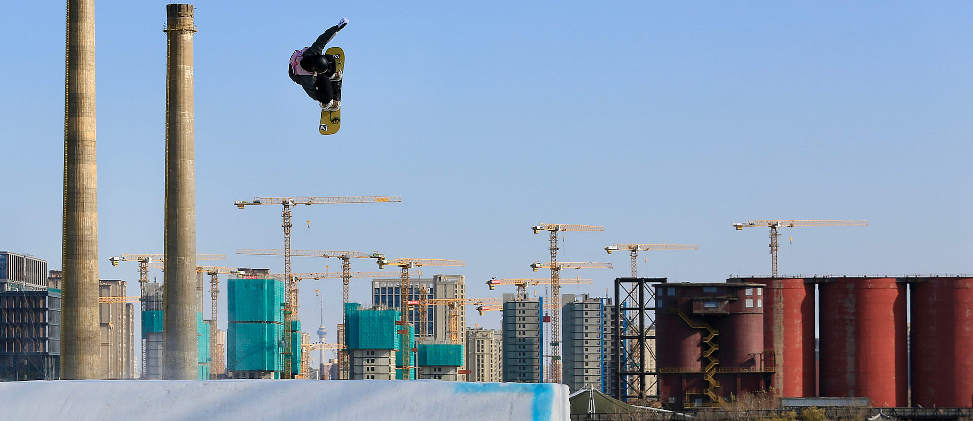 Snowboarder in front of building cranes in the Big Air Sprung