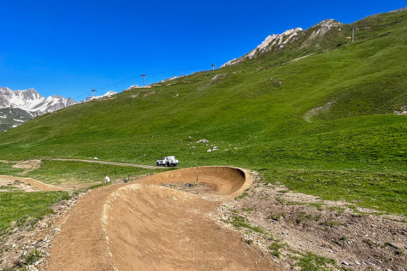 Grand virage relevé sur le trail du Bike Park Tignes avec paysage alpin verdoyant
