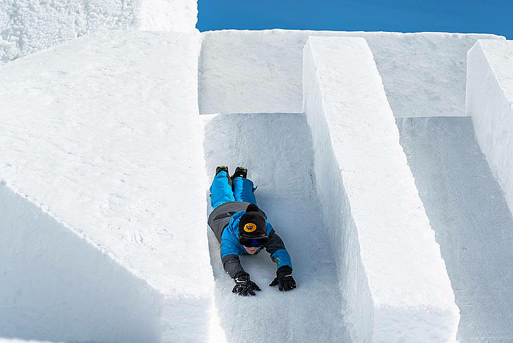 Boy slides head first down a short snow slide