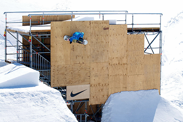 Snowboarder befindet sich vertikal an einem Aufbau aus Metall und Holz