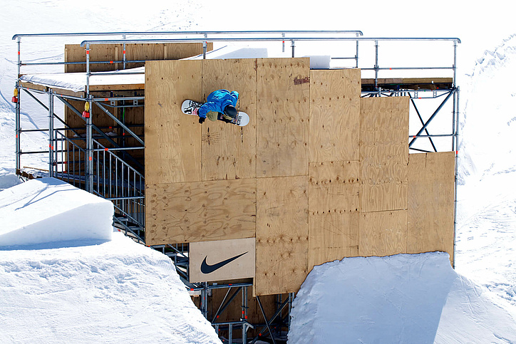 Snowboarder is located vertically on a structure of metal and wood
