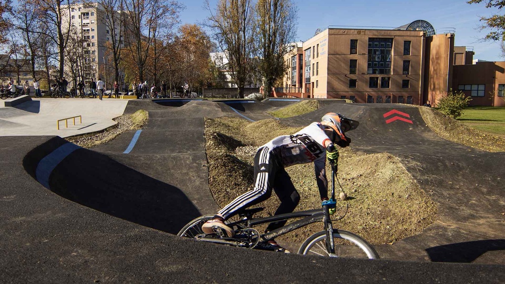 Biker fährt Pumptrack Tarbes mit Hintergrund Gebäuden