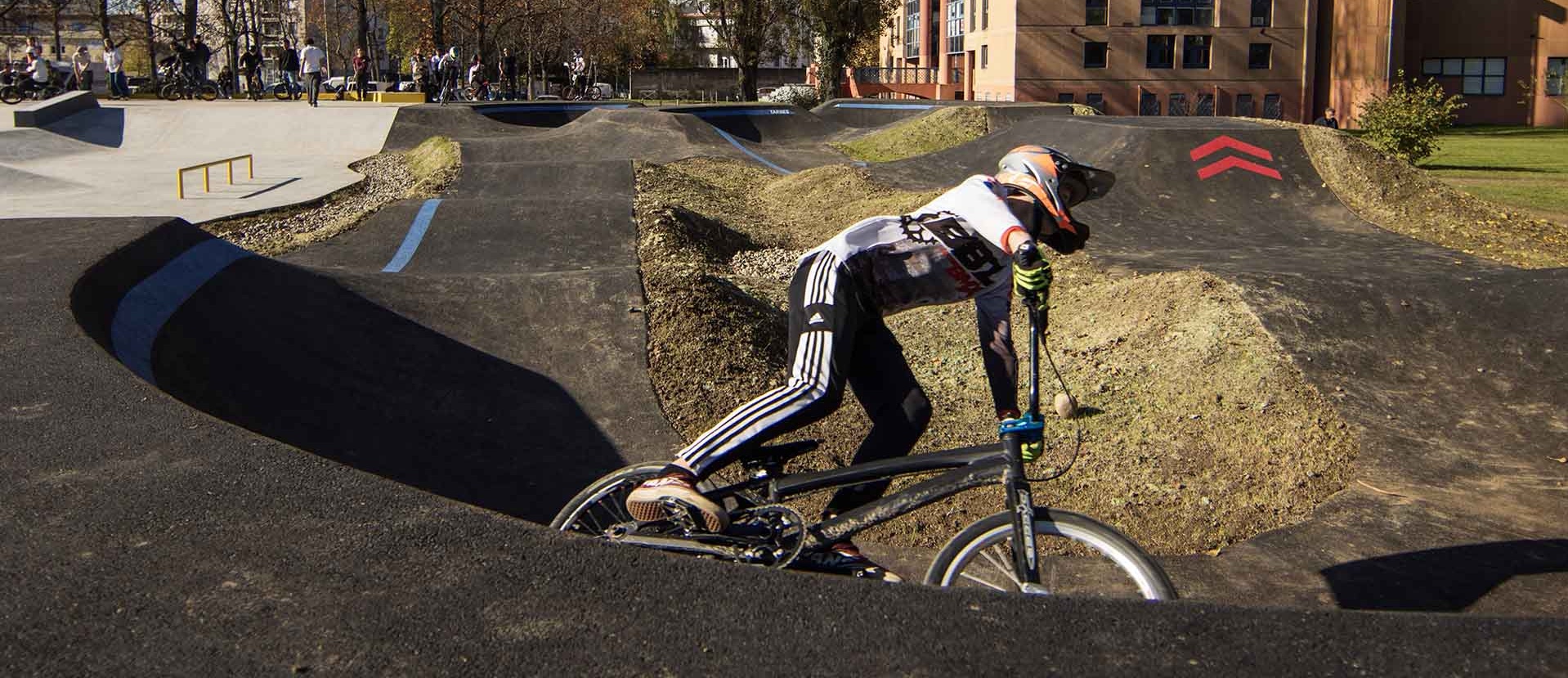 Biker riding Pumptrack Tarbes with buildings in background