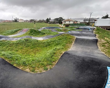 Wide-angle overview of the spacious pumptrack in Saint-Geniès-Bellevue under a cloudy sky.