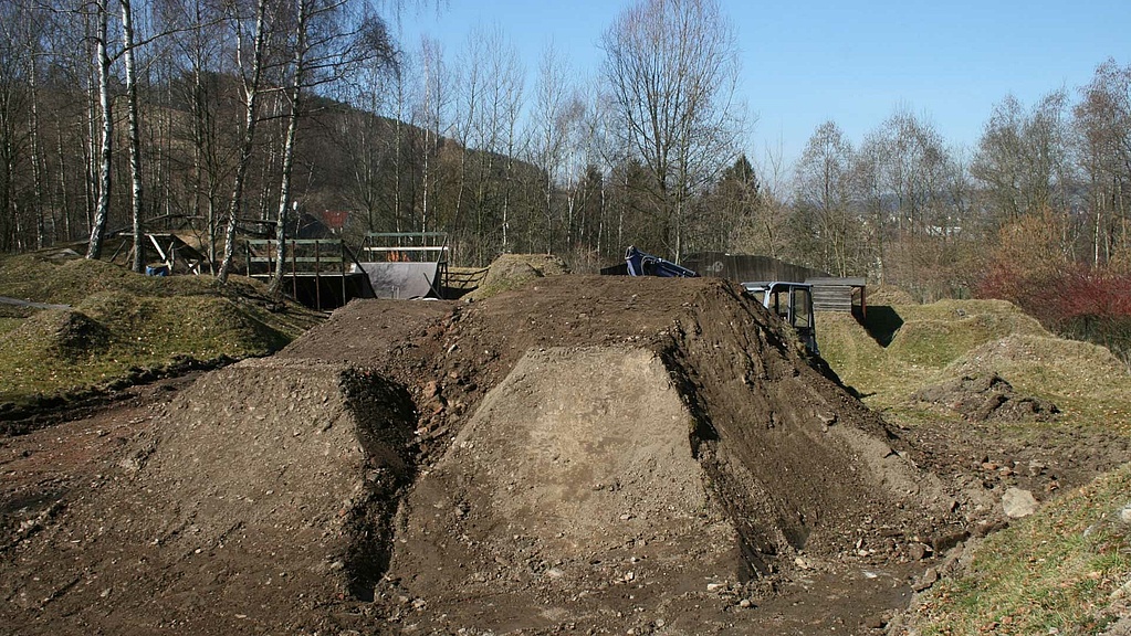 Dirt park with blue sky and forest in background