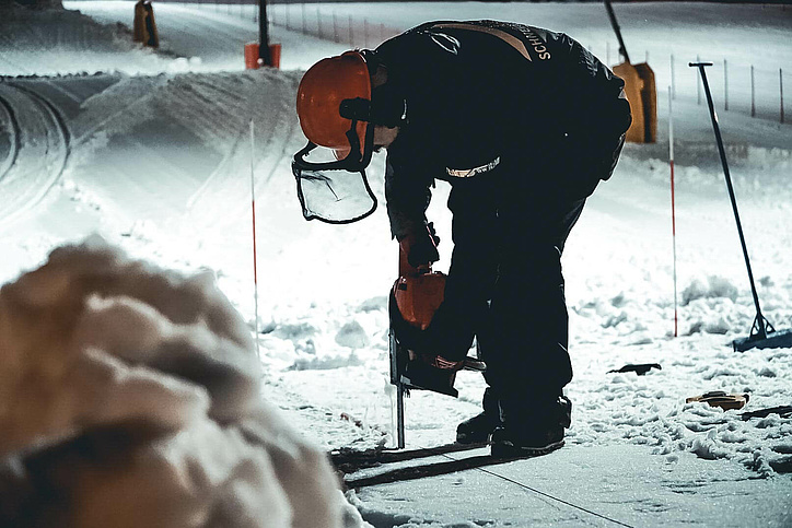 Worker with safety clothing drills in the snow