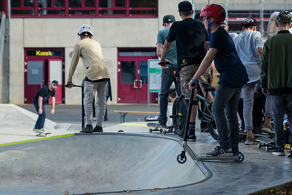 Teenagers with scooters waiting to go to the bowl