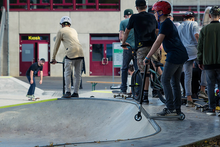 Teenagers with scooters waiting to go to the bowl