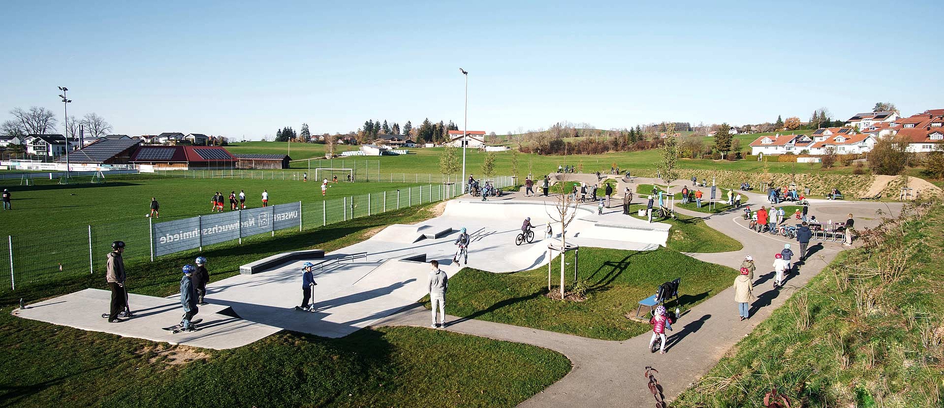 Multifunctional urban sports park in Durach with skatepark, pumptrack and play area for all age groups on a sunny day.