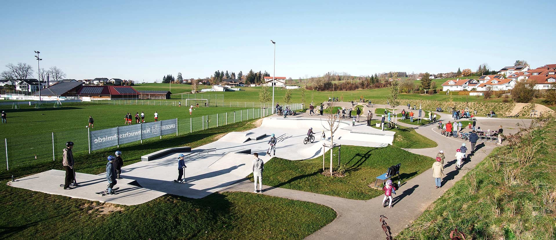 Multifunktionaler Urban Sports Park in Durach mit Skatepark, Pumptrack und Spielbereich für alle Altersgruppen bei sonnigem Wetter.