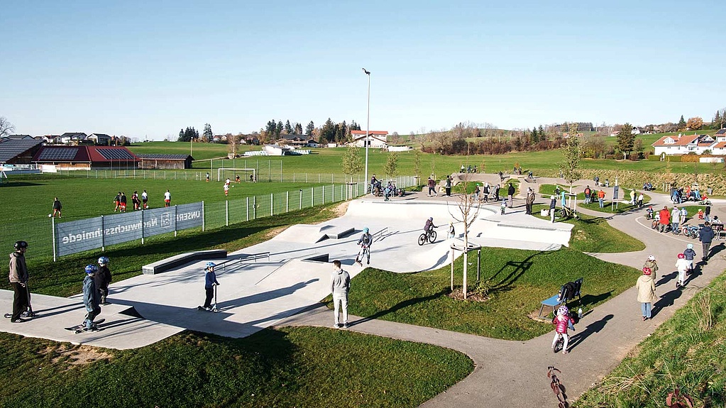 Multifunctional urban sports park in Durach with skatepark, pumptrack and play area for all age groups on a sunny day.