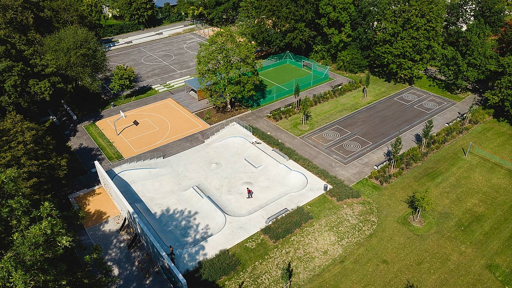Drone image of skate park and sports fields surrounded by meadow and trees