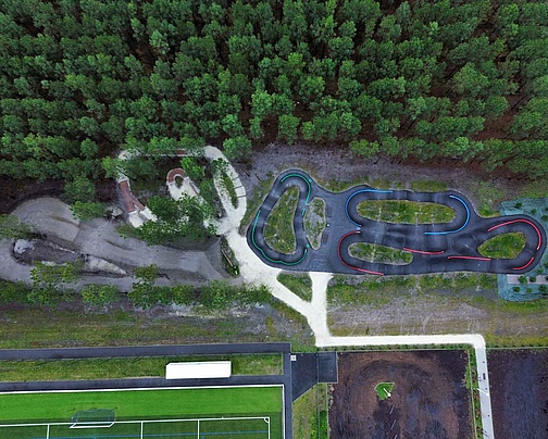Vue grand angle du Pumptrack Audenge, pistes en asphalte noir avec des îlots verts