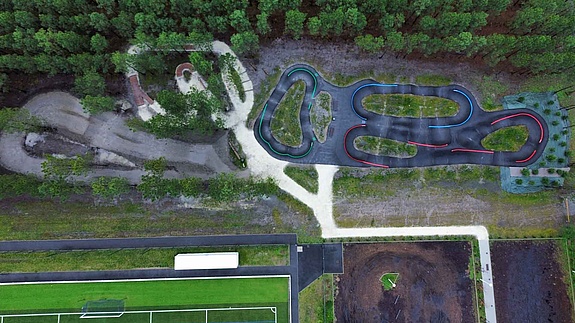 Wide-angle view of Pumptrack Audenge, black asphalt tracks with green islands