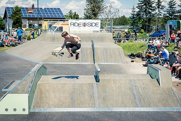 Skateboarder mit Helm springt über eine Box in einem Skatepark