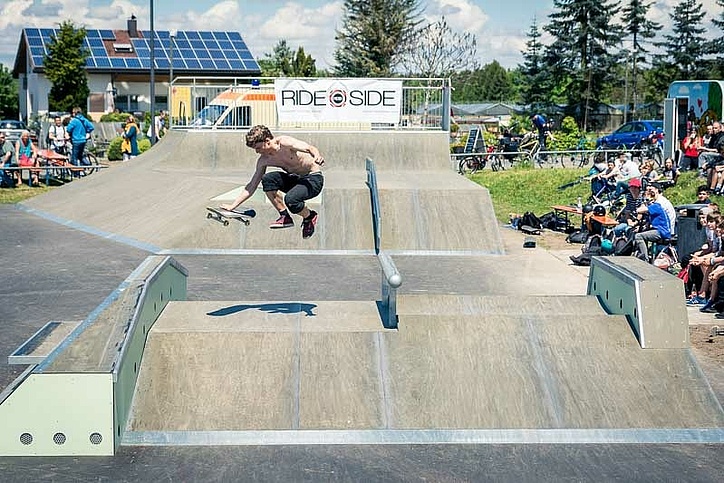 Skateboarder mit Helm springt über eine Box in einem Skatepark