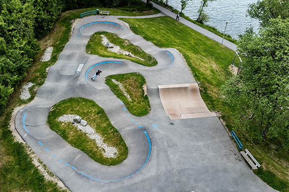 Pumptrack Wackersberg als Luftaufnahme am Seeufer mit asphaltierten Kurven und Wellen