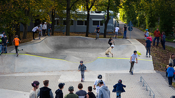 Kids ride in skate park Hennef and other kids watch