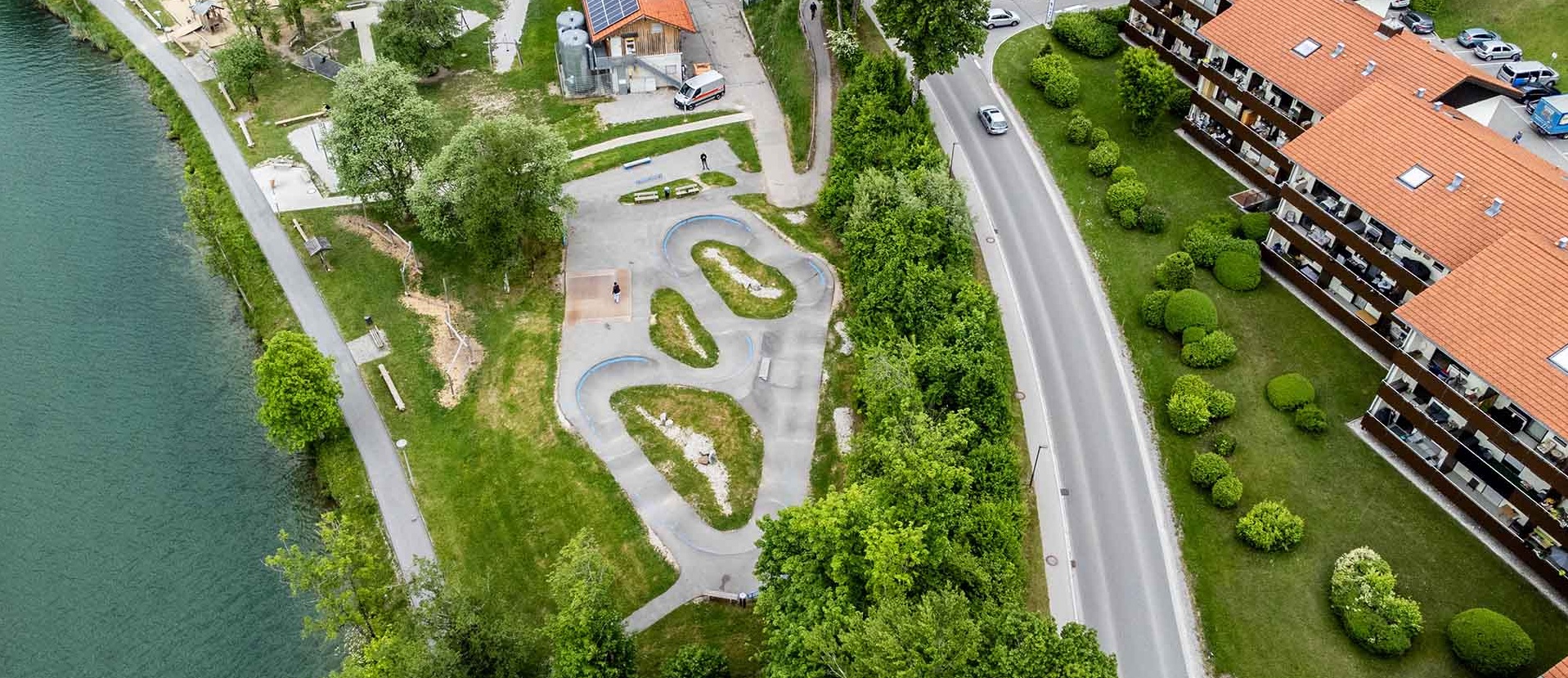 Wide aerial: pump track Wackersberg set in parkland next to residential area