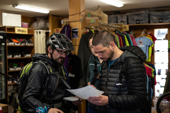 Three people standing in a store looking at a sheet of paper