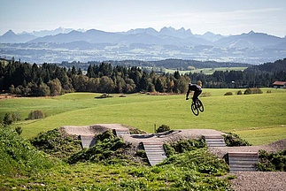 Mountainbiker springt mit Panorama im Hintergrund