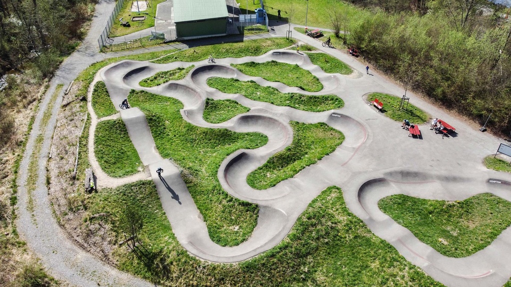 Cyclist on the pump track at Engelhaldepark Kempten with winding asphalt lines
