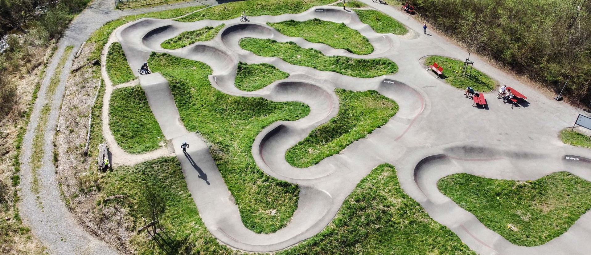 Cyclist on the pump track at Engelhaldepark Kempten with winding asphalt lines