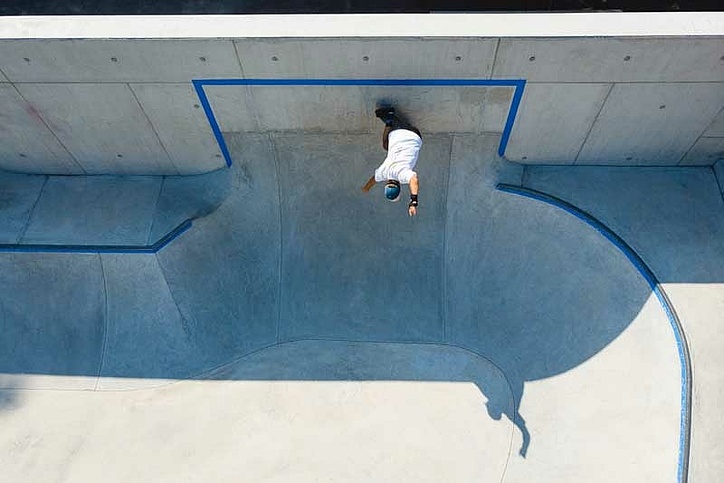Drohnenbild von Skateboarder wie er einen Trick in einem Ortbeton Skatepark macht