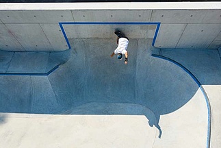 Drohnenbild von Skateboarder wie er einen Trick in einem Ortbeton Skatepark macht
