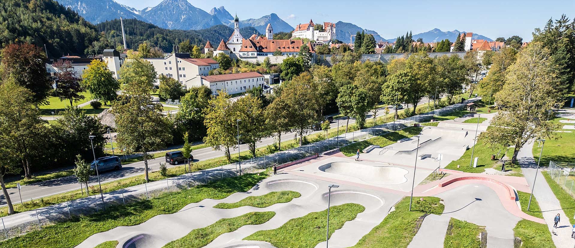  Panoramic view over the Urban Sports Park Füssen with a view of the mountains and Neuschwanstein Castle.