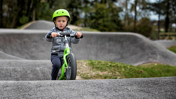 Kind mit Laufrad auf Laufradtrack