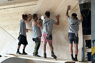 Vier Handwerker montieren Holzelemente beim Bau der Skatehalle Mühlhausen