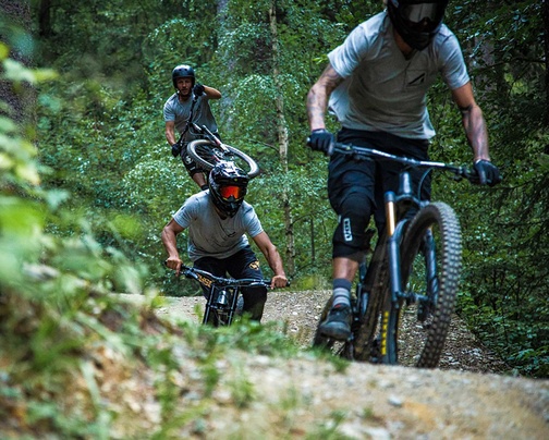 Three bikers in full gear ride one after another on jumpline
