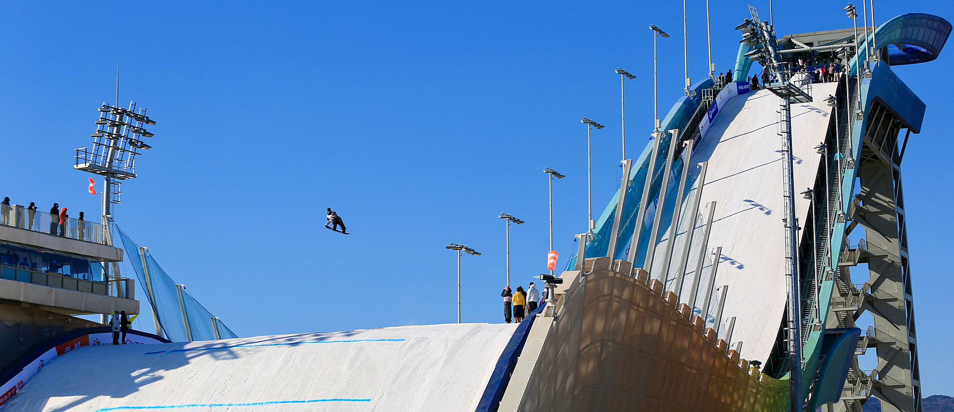 Big-air hill from below with large kicker and city backdrop
