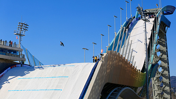 Big-air hill from below with large kicker and city backdrop