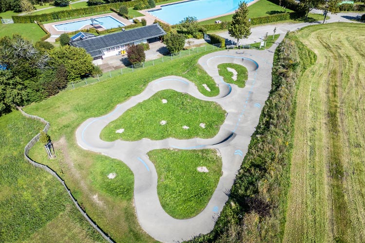 Pumptrack aus der Vogelperspektive neben Schwimmbad